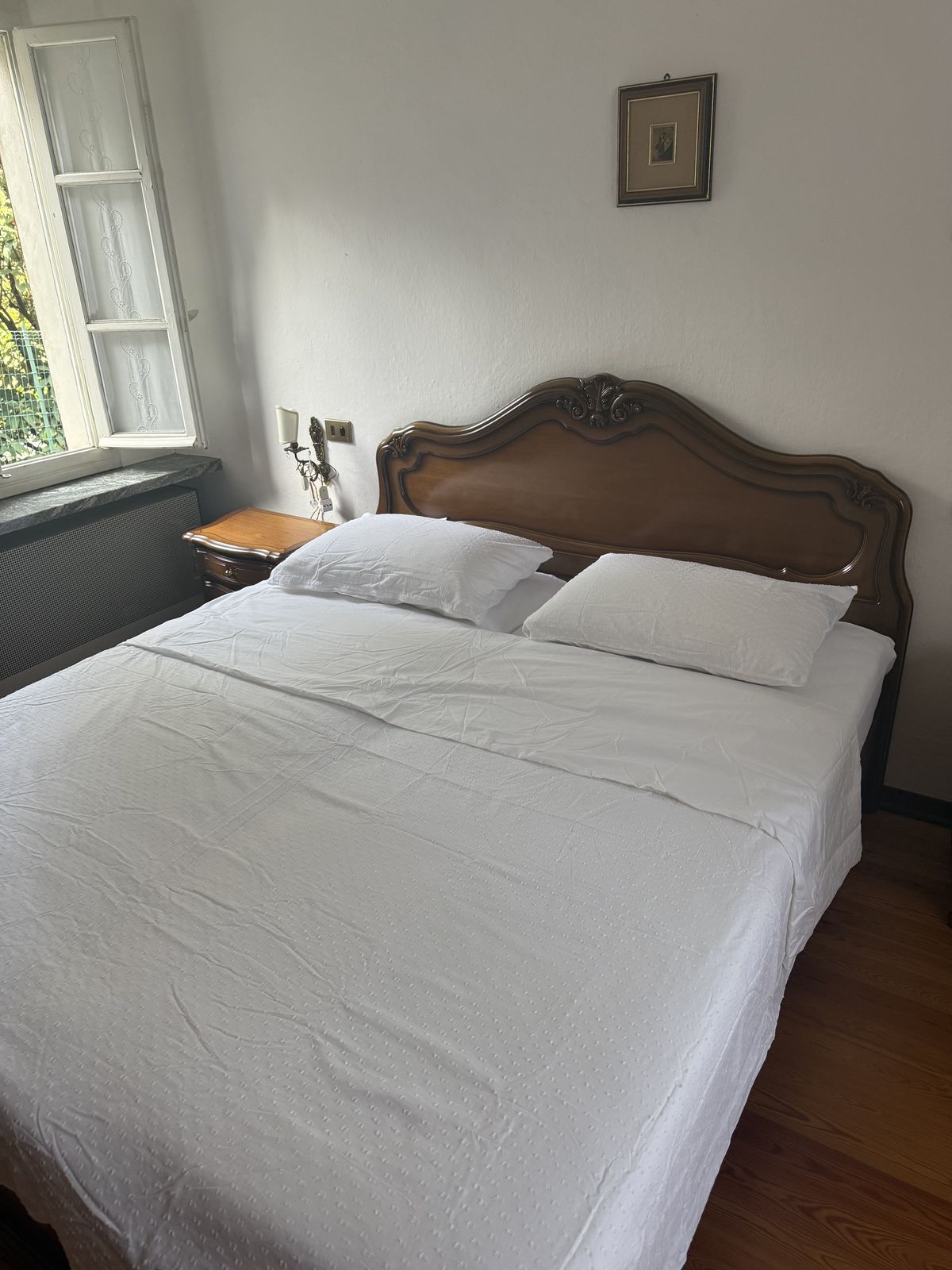 Tweepersoonsbed met houten hoofdeinde in de grote slaapkamer